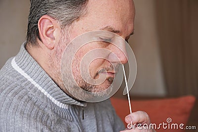 man collecting nasal mucus sample from nose with cotton swab for covid-19 coronavirus self testing at home Stock Photo