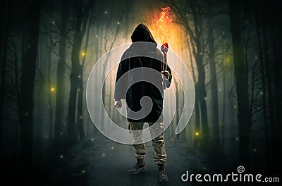 Man coming from dark forest with burning flambeau in his hand concept Stock Photo