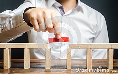 A man is completing the construction of a bridge. Build bridges, make connections and useful contacts. Improving and developing Stock Photo