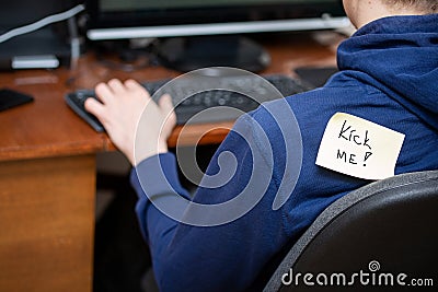 Man at computer with attached note. Kick me. Stock Photo