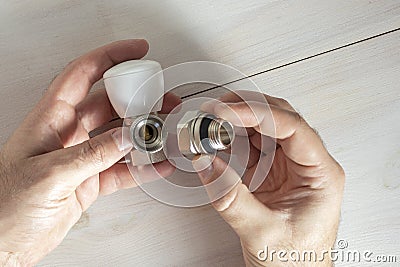 A man connects two parts of a heating radiator faucet. Stock Photo