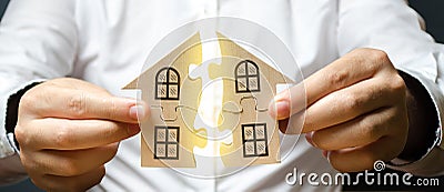 A man connects two puzzles into a whole house above the inscription Mortgage. Construction of your own residential building. Stock Photo