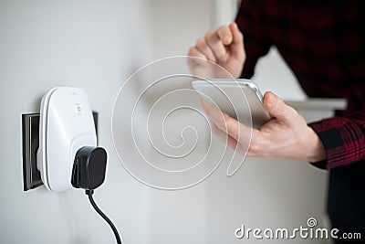 Man Controlling Smart Plug Using App On Mobile Phone Stock Photo