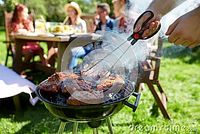 Man cooking meat on barbecue grill at summer party Stock Photo