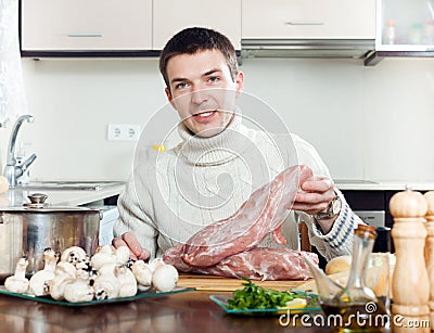 Man cooking meat with mushrooms and potatoes. Adding champign Stock Photo