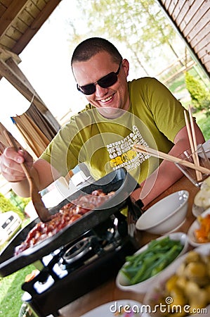 Man cooking outdoors Asian style food, korean meat on the portable stove Stock Photo