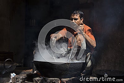 Man cooks in old wok the fire in street market. Pushkar, India Editorial Stock Photo