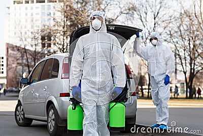 Man in coronavirus hazmat suit carrying disinfection gas Stock Photo