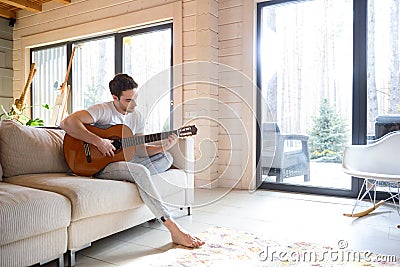 Man on couch with guitar Stock Photo