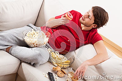 Man on couch with treats Stock Photo