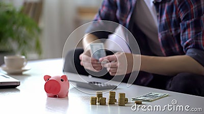Man counting month salary, hiding money from wife into piggy bank, earnings Stock Photo
