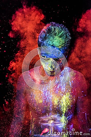 Man covered in glowing powder coming out of red smoke gas Stock Photo