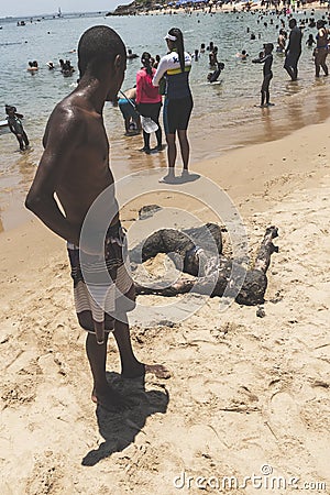 Man covered in oil on the beach at Porto da Barra in Salvador, Bahia, Brazil Editorial Stock Photo
