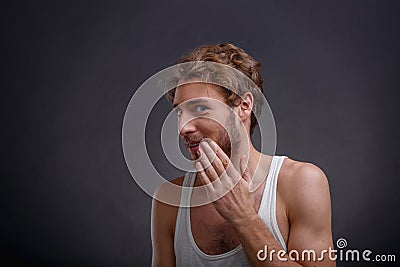 The man covers his mouth with his hand on a black background Stock Photo