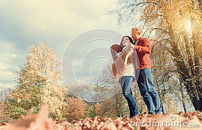 Man covers his wife shoulders with warm shawl in autumn park Stock Photo