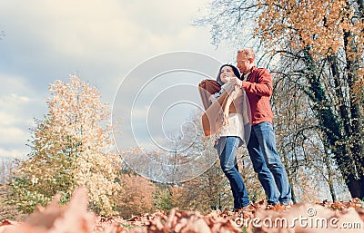 Man covers his wife shoulders with warm shawl in autumn park Stock Photo