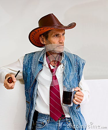 Man in cowboy hat with mug and pipe Stock Photo