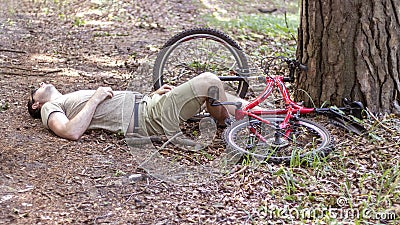 A man crashed into a tree while cycling in forest and lost consciousness. An accident while cycling. Stock Photo