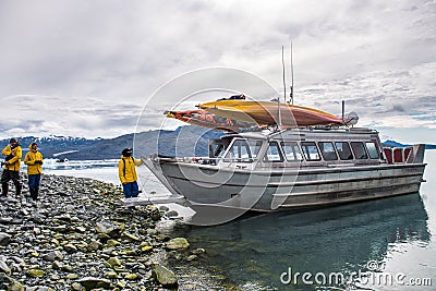 Man with crew members from scientific expedition unload the vessel docked on iceberg rock bay at wintertime to explore the island Stock Photo