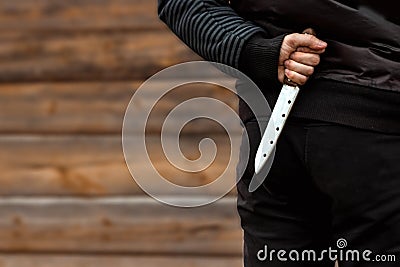 A man, a criminal in black clothes, holds a large knife in his hand. Close-up, copy space. The concept of crime, violation of the Stock Photo