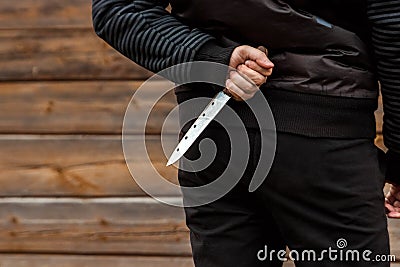 A man, a criminal in black clothes, holds a large knife in his hand. Close-up, copy space. The concept of crime, violation of the Stock Photo