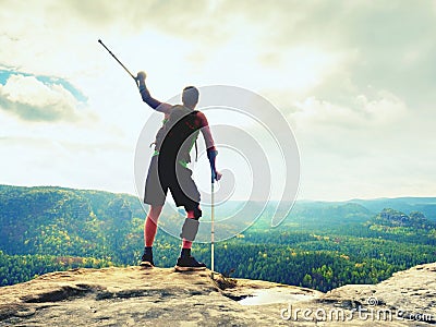 Man with a crutches and fixed broken leg on crutches. Traveler with hurt leg in bandages stay on rock Stock Photo