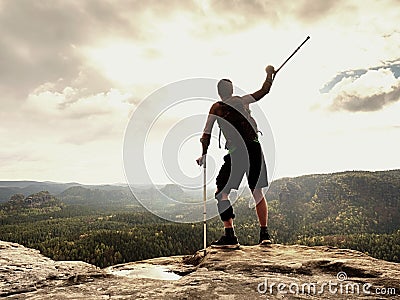 Man with a crutches and fixed broken leg on crutches. Traveler with hurt leg in bandages stay on rock Stock Photo