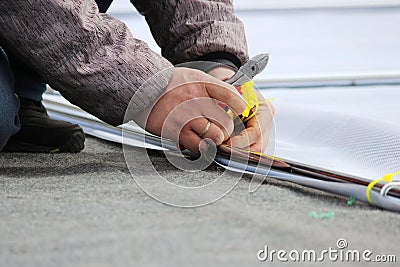 The man cuts the plastic ties of the clamps with the pliers of the wire cutters during the dismantling of the stage after the holi Stock Photo