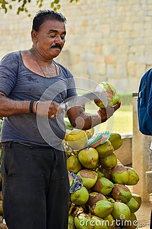 Man cutting coconut with bill hook knife in Kerala Editorial Stock Photo