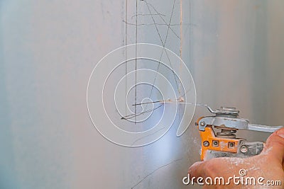 Man is cutting gypsum board with electro knife repair works renovation in restoration indoors. Drywall panel Stock Photo