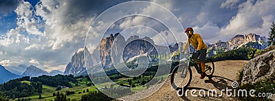 Man cycling on electric bike, rides mountain trail. Man riding on bike in Dolomites mountains landscape. Cycling e-mtb enduro Stock Photo