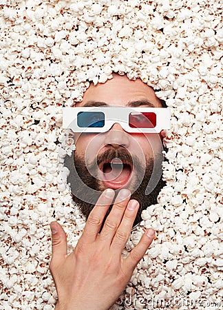 Man in 3-D glasses lying in popcorn Stock Photo