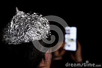 Man in the dark wearing a tin foil hat Stock Photo