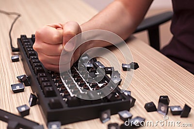 Man decisively destroys a mechanical computer keyboard in rage using one fist Stock Photo