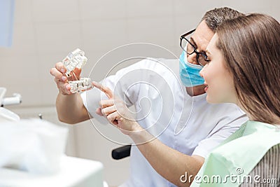 Man dentist show dentures teeth at dental surgery to patient Stock Photo