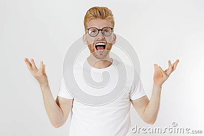 Man Depression signs and Symptoms. Young redheaded guy with red beard and white t shirt shouting hard and angry. Failed startup Stock Photo