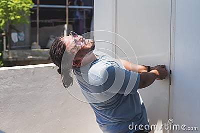 A man desperately pulls on a locked door in a futile attempt to get inside the public restroom. Pulling with all his might and Stock Photo