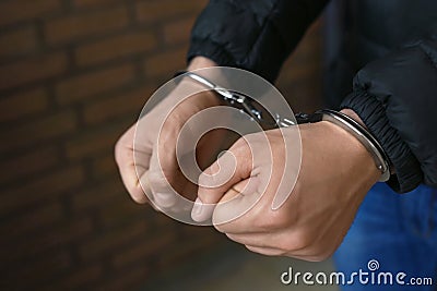 Man detained in handcuffs indoors, closeup view. Stock Photo