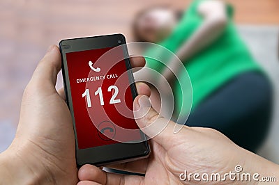 Man dialing emergency (112 number) on smartphone. Woman had hear Stock Photo