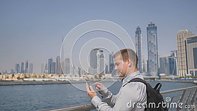 The man dials the number on the phone and talks on the background of the panorama of Dubai. Hand close-up. Stock Photo