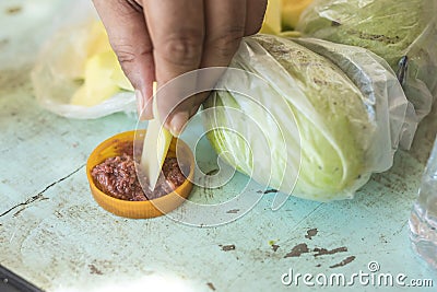 A man dips a slice of green mango into bagoong, a condiment made with fermented fish, krill or shrimp paste Stock Photo