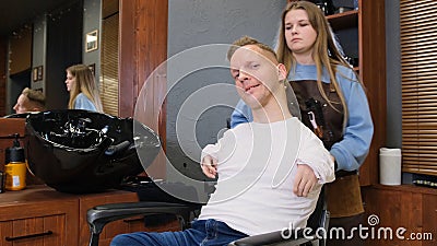 a man with disabilities gets his hair cut and styled in a barber shop. Stock Photo