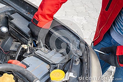 Man disconnecting the terminal on the car battery under the open hood of a Flat-four car engine Stock Photo