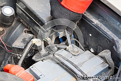 Man disconnecting the terminal on the car battery under the open hood of a Flat-four car engine Stock Photo