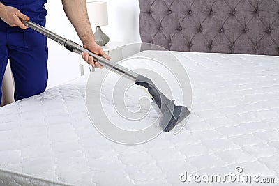 Man disinfecting mattress with vacuum cleaner Stock Photo