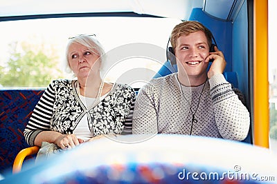 Man Disturbing Passengers On Bus Journey With Loud Music Stock Photo