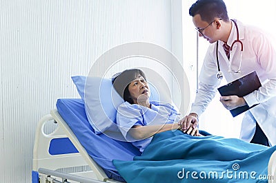 Man doctor checking pressure of female patient, Older sick woman patient lay on bed in hospital with intravenous normal saline Stock Photo