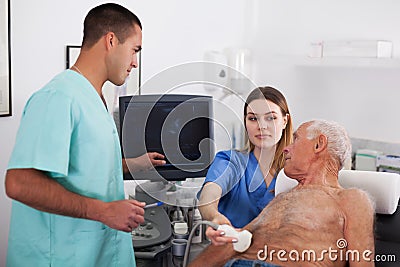 Man doctor and female nurse examines elderly man Stock Photo