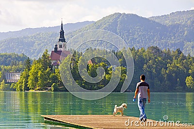 Man with a dog walks on the pier of Lake Bled, Slovenia Editorial Stock Photo