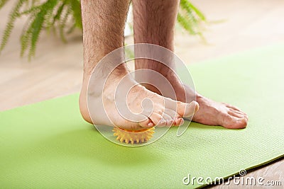 Man doing flatfoot correction gymnastic exercise using massage ball at home Stock Photo